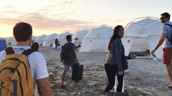 Fyre festival attendees walk towards emergency shelter tents